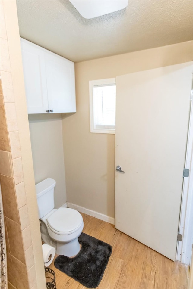 bathroom with hardwood / wood-style flooring, toilet, and a textured ceiling