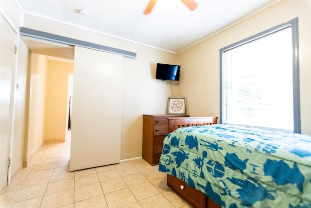 tiled bedroom with ornamental molding and ceiling fan