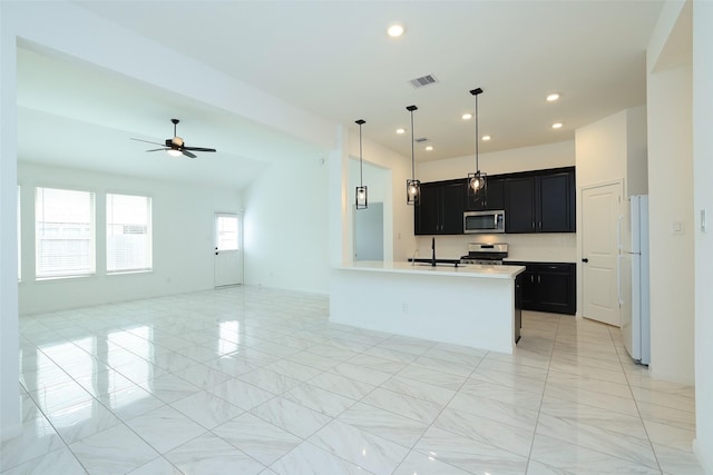 kitchen with stainless steel appliances, visible vents, light countertops, open floor plan, and dark cabinets