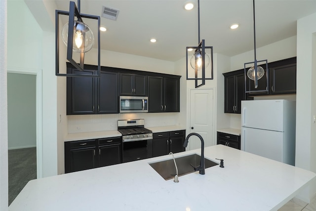 kitchen with light countertops, appliances with stainless steel finishes, a sink, and dark cabinets