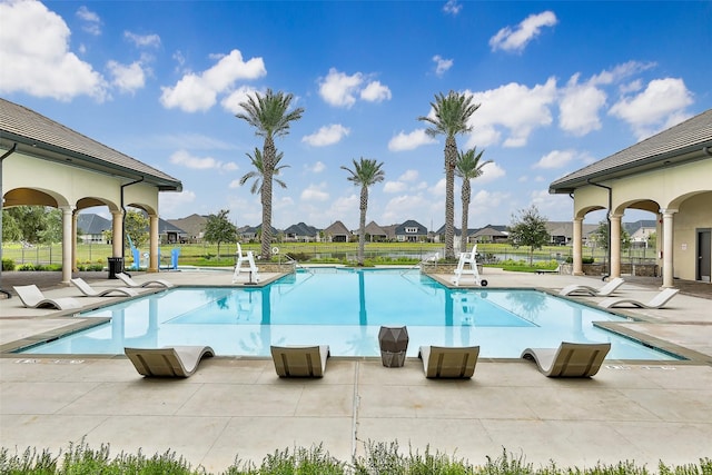 community pool with a residential view, a patio area, and fence