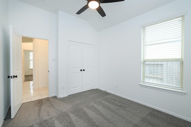 unfurnished bedroom featuring vaulted ceiling, carpet floors, a closet, and baseboards