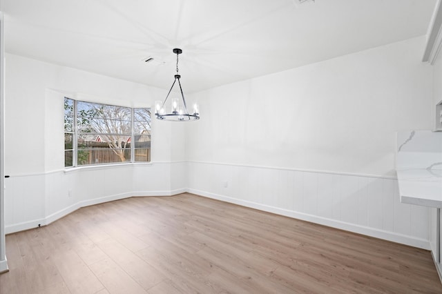 unfurnished dining area with hardwood / wood-style floors and a chandelier