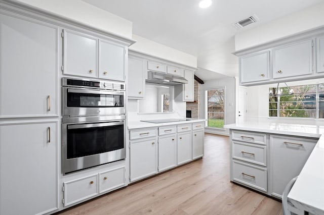 kitchen featuring black electric cooktop, stainless steel double oven, and light hardwood / wood-style floors