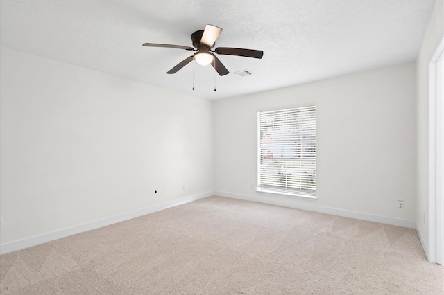 spare room with ceiling fan, light carpet, and a textured ceiling