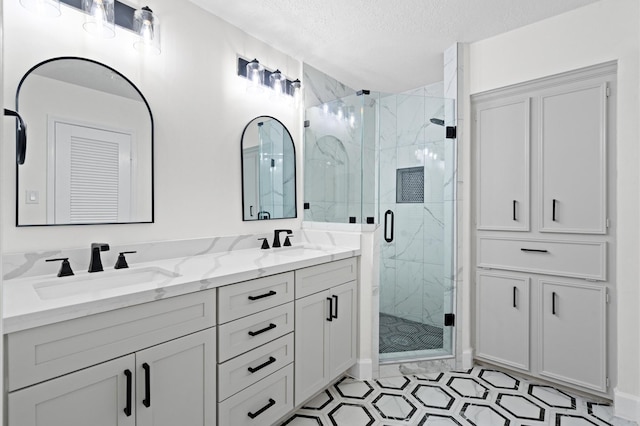 bathroom with vanity, a shower with door, and a textured ceiling