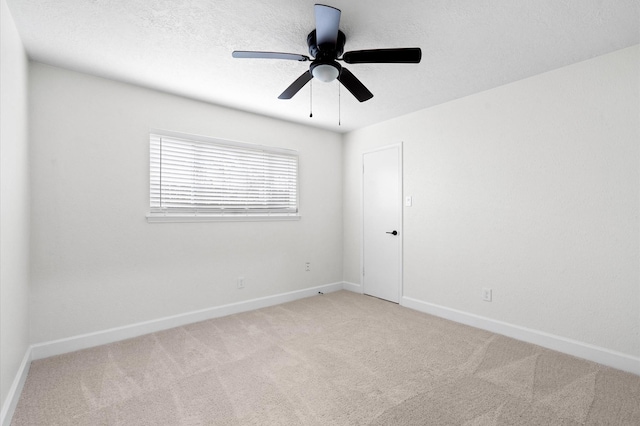 empty room with light carpet, ceiling fan, and a textured ceiling