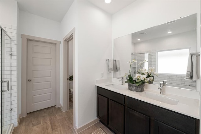 bathroom featuring hardwood / wood-style flooring, vanity, toilet, and a shower with door