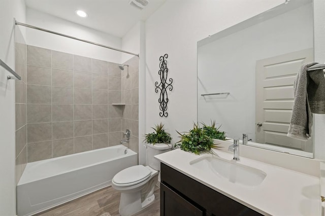 full bathroom with tiled shower / bath, vanity, toilet, and hardwood / wood-style floors