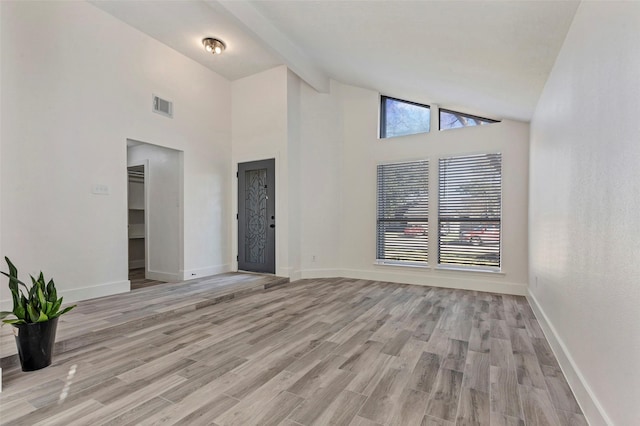 spare room with high vaulted ceiling, light hardwood / wood-style floors, and beamed ceiling