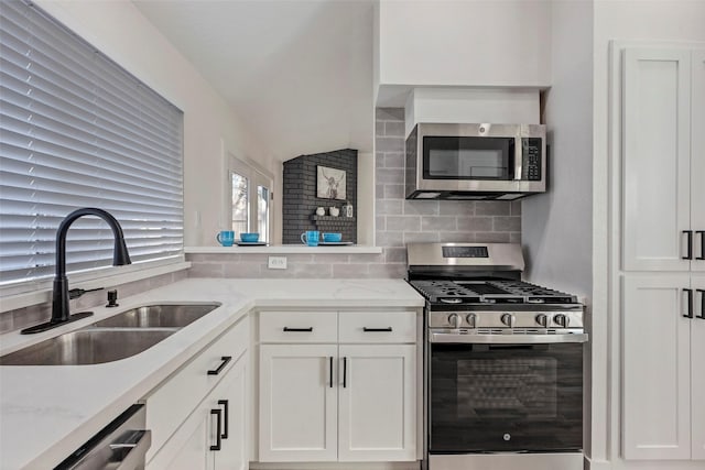 kitchen featuring sink, white cabinetry, stainless steel appliances, light stone countertops, and backsplash