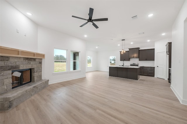 living room with sink, a fireplace, ceiling fan, and light wood-type flooring