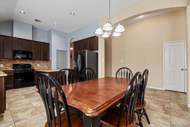 tiled dining space featuring an inviting chandelier and vaulted ceiling