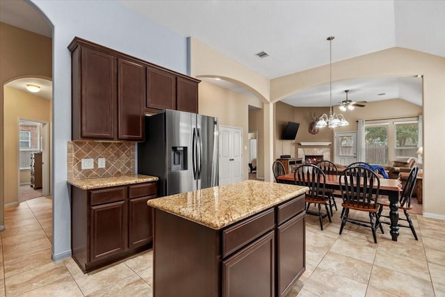 kitchen featuring stainless steel refrigerator with ice dispenser, lofted ceiling, dark brown cabinetry, decorative light fixtures, and a center island