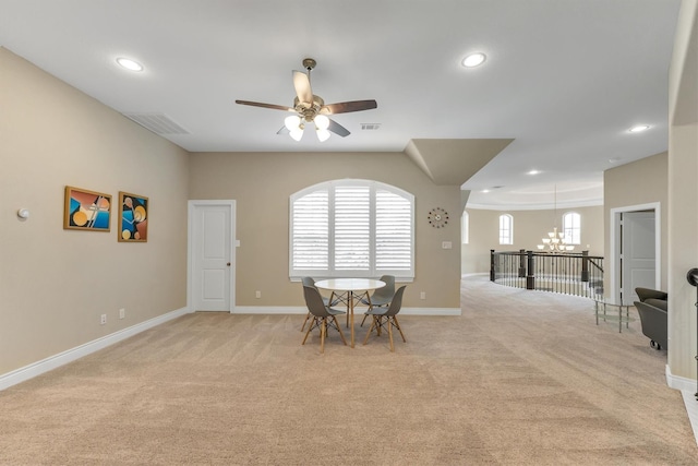 carpeted dining room with ceiling fan with notable chandelier and a wealth of natural light