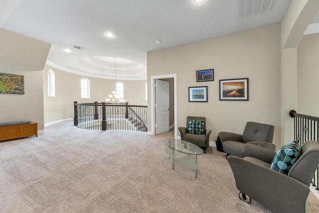 carpeted living room with an inviting chandelier and a tray ceiling