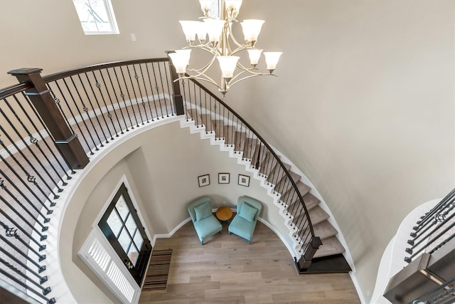 staircase with a towering ceiling, a chandelier, and hardwood / wood-style floors