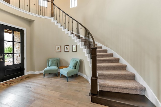 entrance foyer featuring a towering ceiling and light wood-type flooring