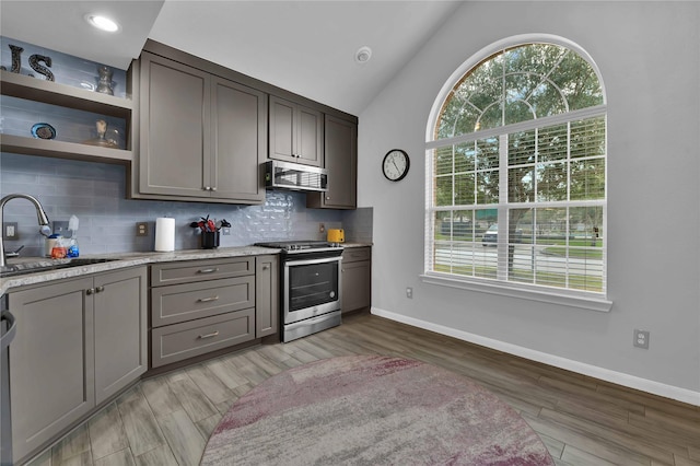 kitchen featuring lofted ceiling, sink, tasteful backsplash, light hardwood / wood-style floors, and gas range