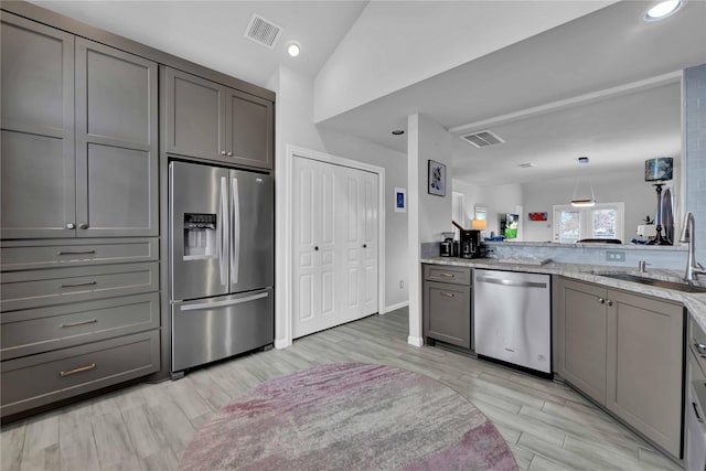 kitchen featuring gray cabinetry, sink, light stone counters, and stainless steel appliances