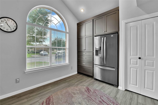 kitchen with lofted ceiling, dark brown cabinetry, stainless steel fridge with ice dispenser, and plenty of natural light