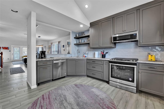 kitchen featuring backsplash, stainless steel appliances, vaulted ceiling, and gray cabinetry