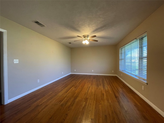 empty room with ceiling fan, dark hardwood / wood-style floors, and a textured ceiling