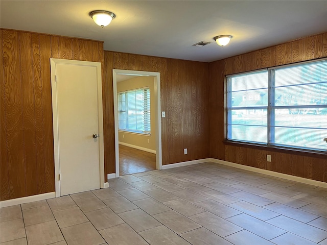 unfurnished room with light tile patterned floors and wood walls