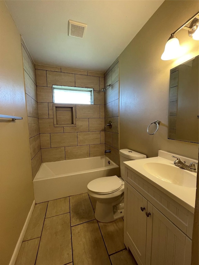 full bathroom with tiled shower / bath, vanity, and toilet