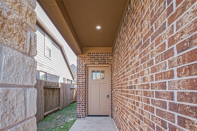 property entrance with fence and brick siding