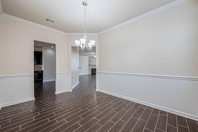 unfurnished room featuring a large fireplace, visible vents, an inviting chandelier, dark wood finished floors, and crown molding