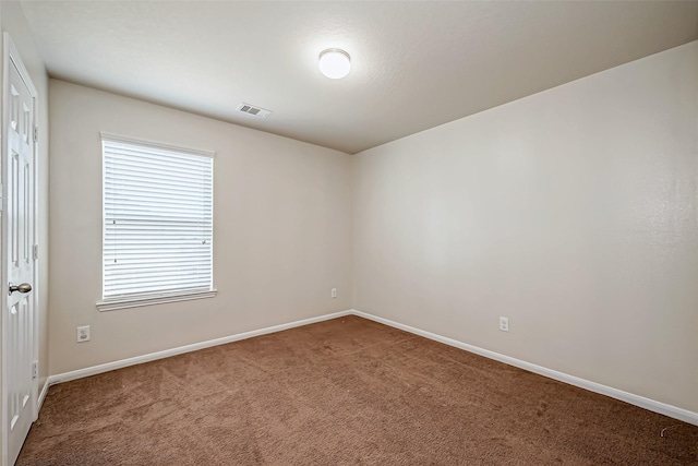 empty room featuring carpet, visible vents, and baseboards