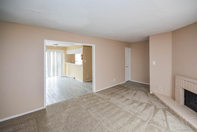 unfurnished living room with carpet flooring and a brick fireplace