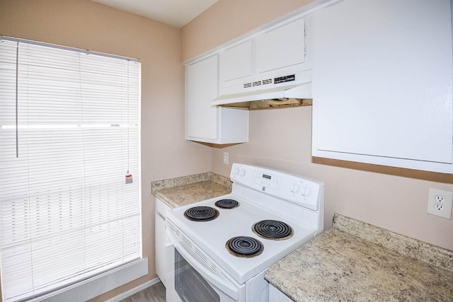 kitchen with electric stove and white cabinetry