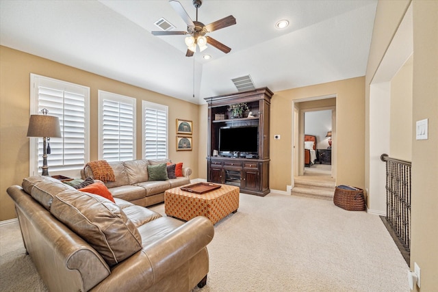 living room with ceiling fan, vaulted ceiling, and light carpet