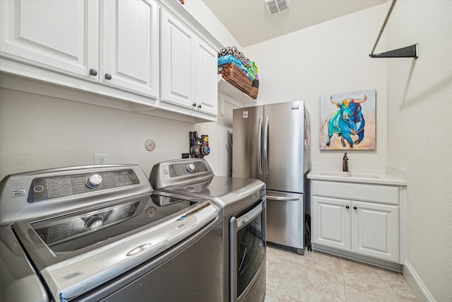 clothes washing area with separate washer and dryer, sink, and light tile patterned floors