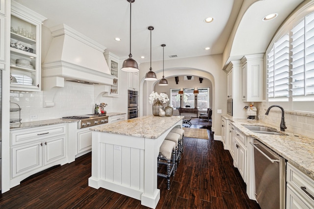 kitchen featuring pendant lighting, sink, stainless steel appliances, a center island, and custom exhaust hood