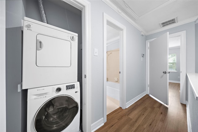 washroom with crown molding, dark wood-type flooring, and stacked washer / dryer