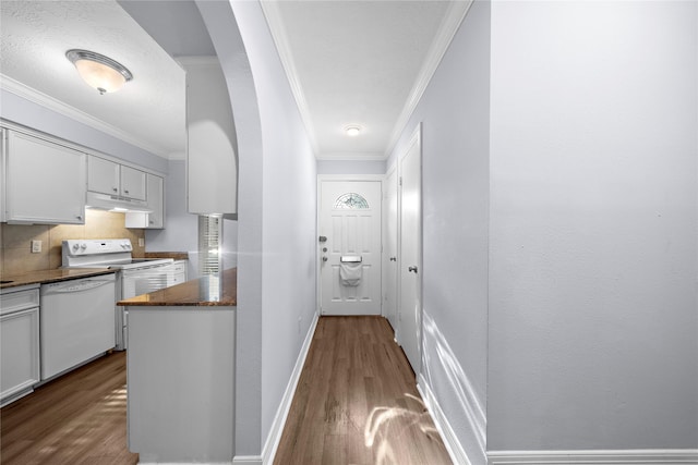 kitchen featuring dark wood-type flooring, white appliances, crown molding, and white cabinets