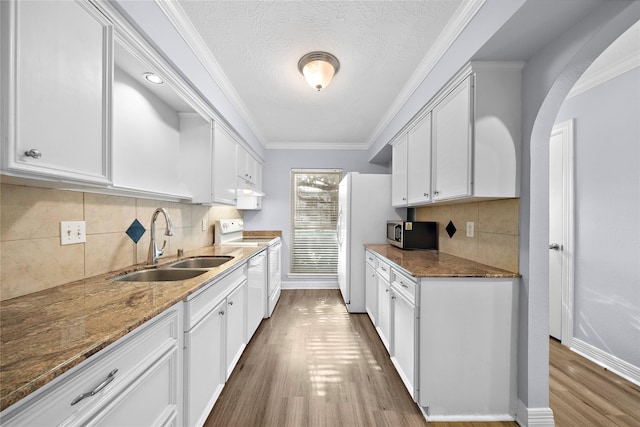 kitchen with sink, white cabinets, white appliances, and dark stone counters