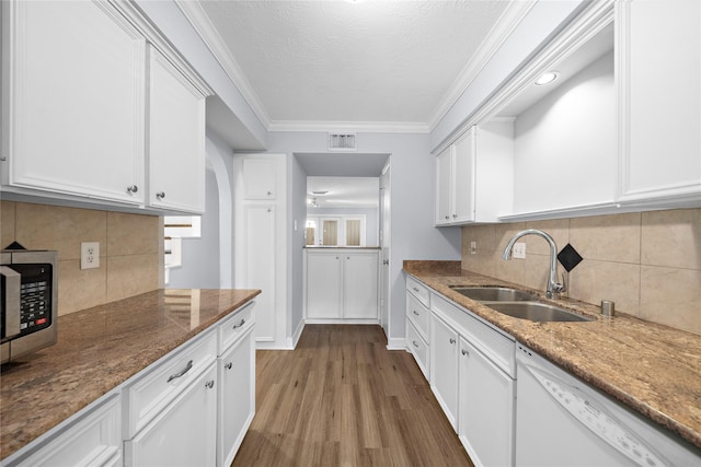 kitchen with sink, white cabinets, dark stone counters, white dishwasher, and light wood-type flooring