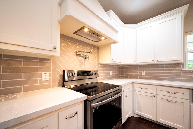 kitchen with custom exhaust hood, tasteful backsplash, white cabinets, and stainless steel electric range