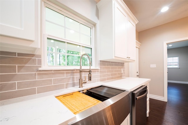 kitchen featuring white cabinetry, backsplash, stainless steel dishwasher, and a healthy amount of sunlight