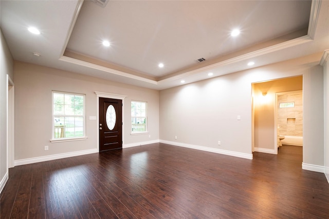 foyer entrance with ornamental molding, dark wood-type flooring, and a tray ceiling