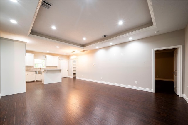 unfurnished living room featuring dark hardwood / wood-style flooring, crown molding, and a raised ceiling