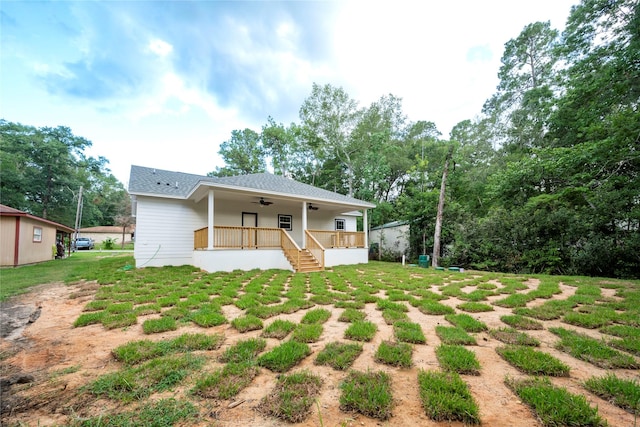 back of property with a yard, ceiling fan, and covered porch