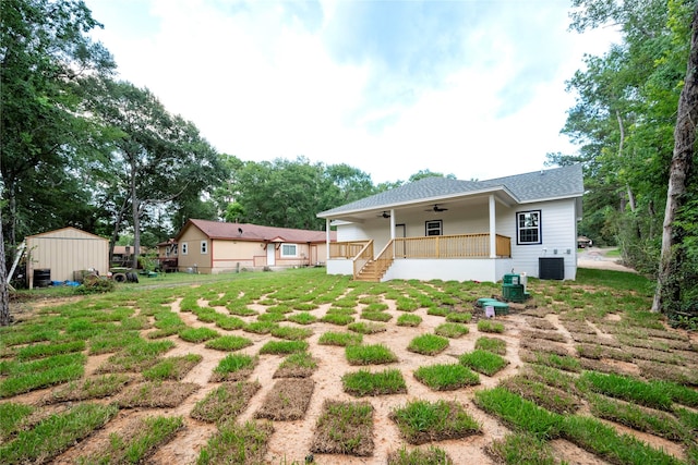 rear view of house featuring ceiling fan, central air condition unit, covered porch, and a lawn