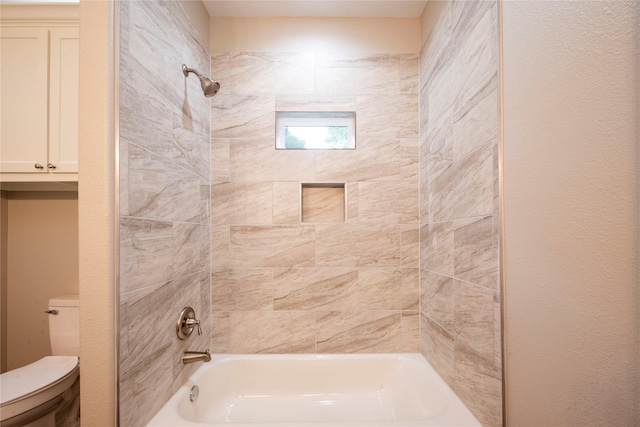 bathroom featuring tiled shower / bath combo and toilet