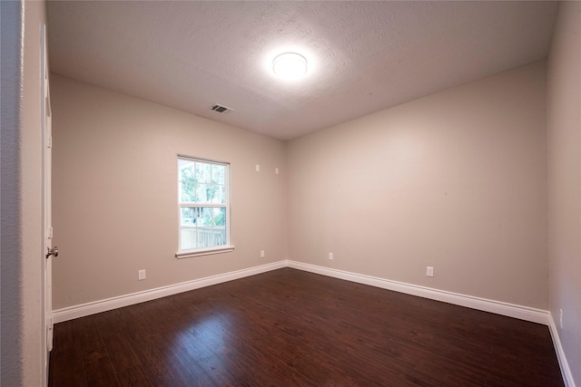 spare room with dark hardwood / wood-style flooring and a textured ceiling