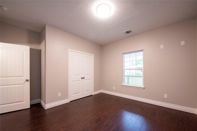 unfurnished bedroom featuring a textured ceiling and dark hardwood / wood-style flooring